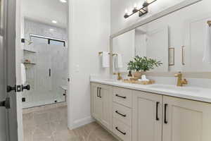 Bathroom featuring double vanity, a stall shower, marble look tiles, and recessed lighting