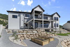 Rear view of house with a balcony, a garden, and stairway