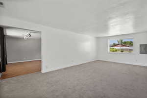 Unfurnished living room with carpet flooring, electric panel, and a textured ceiling