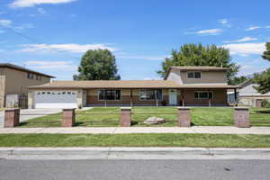 Traditional-style home featuring a fenced front yard, an attached garage, concrete driveway, brick siding, and a porch