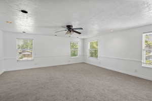 Carpeted empty room featuring healthy amount of natural light, a ceiling fan, a textured ceiling, and recessed lighting