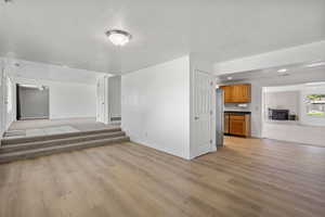 Unfurnished living room featuring light wood-type flooring, stairway, and recessed lighting