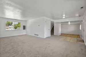 Spare room with stairs, carpet flooring, electric panel, and a textured ceiling