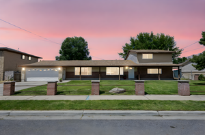 Traditional home with an attached garage, concrete driveway, a fenced front yard, and roof with shingles