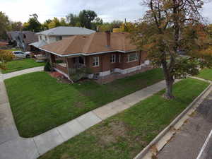 View of front of property featuring a shingled roof, a front lawn, covered porch, and a chimney