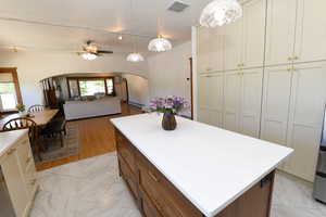 Kitchen with arched walkways, a kitchen island, light marble finish flooring, light countertops, and pendant lighting