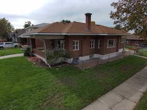 Rear view of property with a chimney, brick siding, and a porch