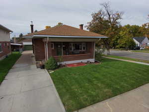 Bungalow-style house featuring a porch, a front yard, and brick siding