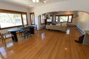 Living room with arched walkways, light wood-style flooring, and baseboard heating