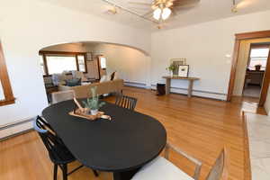 Dining room featuring a textured ceiling, ceiling fan, arched walkways, light wood finished floors, and rail lighting