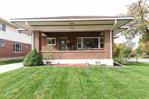 View of front of property featuring a front yard, a porch, and brick siding