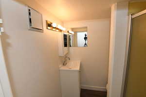 Bathroom with vanity, an enclosed shower, a textured ceiling, and wood finished floors