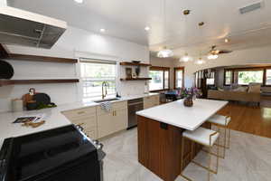 Kitchen featuring electric range oven, pendant lighting, ventilation hood, open floor plan, and a kitchen bar