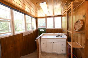 Bathroom with wood walls, wood ceiling, and vanity