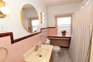 Full bath with tile walls, a wainscoted wall, marble finish flooring, vanity, and a shower with curtain