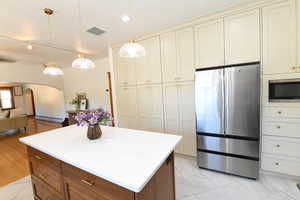 Kitchen with appliances with stainless steel finishes, arched walkways, decorative light fixtures, a kitchen island, and open floor plan