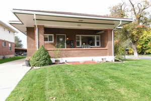 View of front of property featuring a front yard, brick siding, and a porch