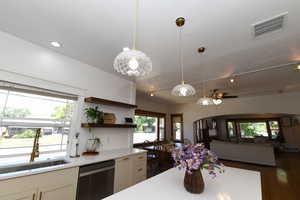 Kitchen with dishwasher, white cabinets, light countertops, and hanging light fixtures