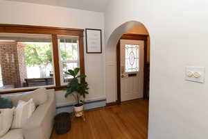 Foyer with wood finished floors, arched walkways, and baseboard heating