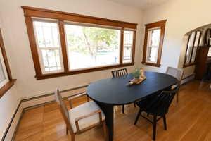 Dining area featuring wood finished floors, a baseboard heating unit, and arched walkways