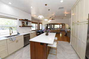 Kitchen featuring arched walkways, a center island, open floor plan, hanging light fixtures, and a breakfast bar