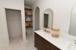 Full bath featuring double vanity, marble finish flooring, and built in features