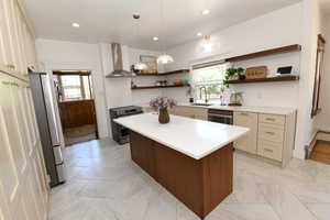 Kitchen with open shelves, light countertops, wall chimney exhaust hood, appliances with stainless steel finishes, and plenty of natural light