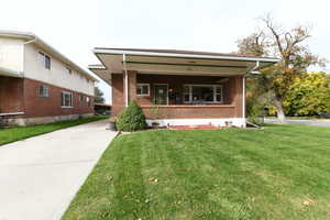 Bungalow-style home featuring a front lawn, brick siding, and covered porch
