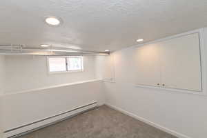 Below grade area with baseboard heating, a textured ceiling, carpet, and recessed lighting