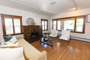 Living room featuring rail lighting, a brick fireplace, plenty of natural light, and hardwood / wood-style floors