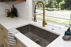 Kitchen view of a sink and light stone counters