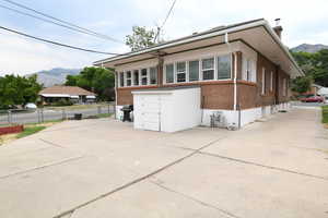 View of front of house featuring brick siding, a mountain view, concrete driveway, and a chimney