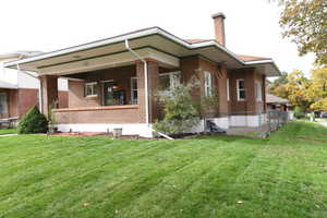 View of front facade featuring a chimney and brick siding