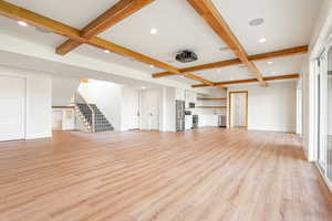 Unfurnished living room featuring beamed ceiling, recessed lighting, coffered ceiling, light wood-type flooring, and stairs