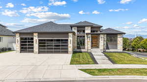View of front of property with stone siding, an attached garage, driveway, and a shingled roof