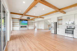 Unfurnished living room with beam ceiling, light wood-style floors, recessed lighting, coffered ceiling, and a fireplace