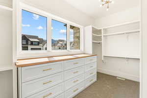 Spacious closet featuring carpet floors and a chandelier