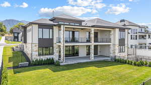 Rear view of property with a balcony, stucco siding, stone siding, and a ceiling fan