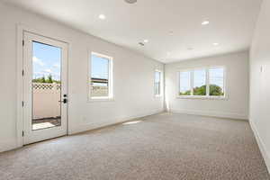 Empty room featuring light carpet, healthy amount of natural light, and recessed lighting