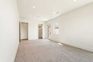 Unfurnished bedroom with light colored carpet, recessed lighting, and ensuite bathroom