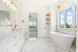 Bathroom featuring vanity, a freestanding bath, marble finish floors, recessed lighting, and tile walls