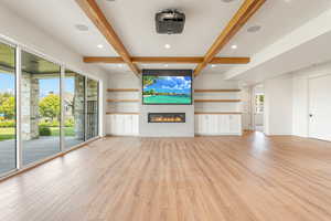 Unfurnished living room with beamed ceiling, recessed lighting, a glass covered fireplace, and light wood-type flooring