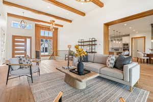 Living room featuring recessed lighting, light wood finished floors, a chandelier, beam ceiling, and a towering ceiling