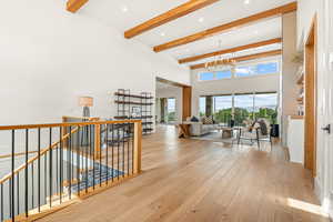 Hall featuring a chandelier, hardwood / wood-style flooring, an upstairs landing, beam ceiling, and a high ceiling