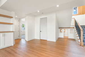 Unfurnished living room with recessed lighting, light wood-style flooring, and stairway
