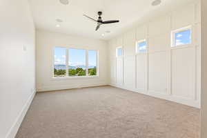Unfurnished room featuring healthy amount of natural light, light colored carpet, a ceiling fan, recessed lighting, and a decorative wall