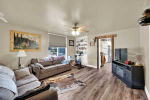Living area featuring wood finished floors, a ceiling fan, built in features, and a textured ceiling