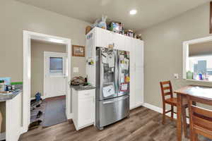 Kitchen with stainless steel fridge with ice dispenser, wood finished floors, white cabinets, and recessed lighting