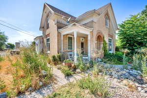 View of front of home with brick siding, covered porch, and a shingled roof