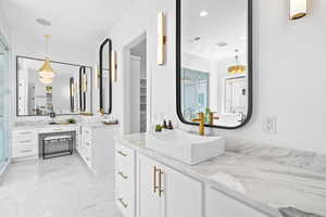 Full bath featuring a stall shower, two vanities, and marble finish floors